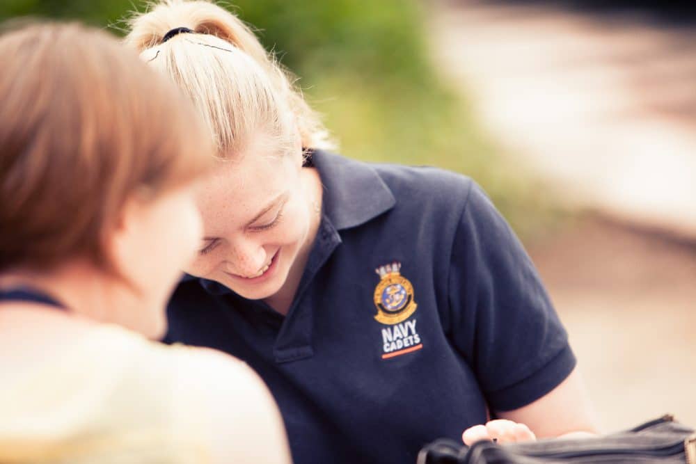 navy cadet helping another student