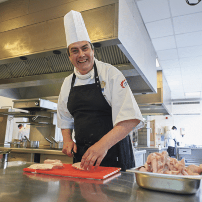 Care home chef cutting chicken