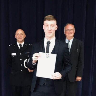 Student standing shows certificate