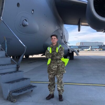Student in RAF uniform standing in front of plane