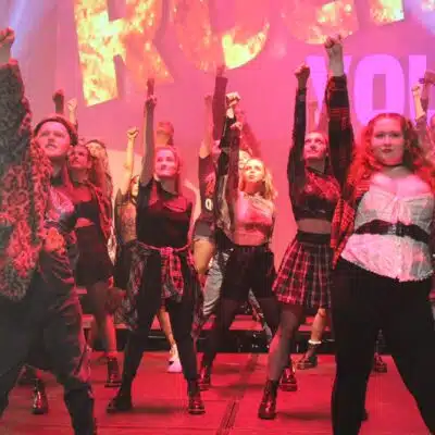 Students standing with one arm in air