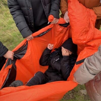 Rescue reinactment with girl in a red sheet, on a college trip outdoors