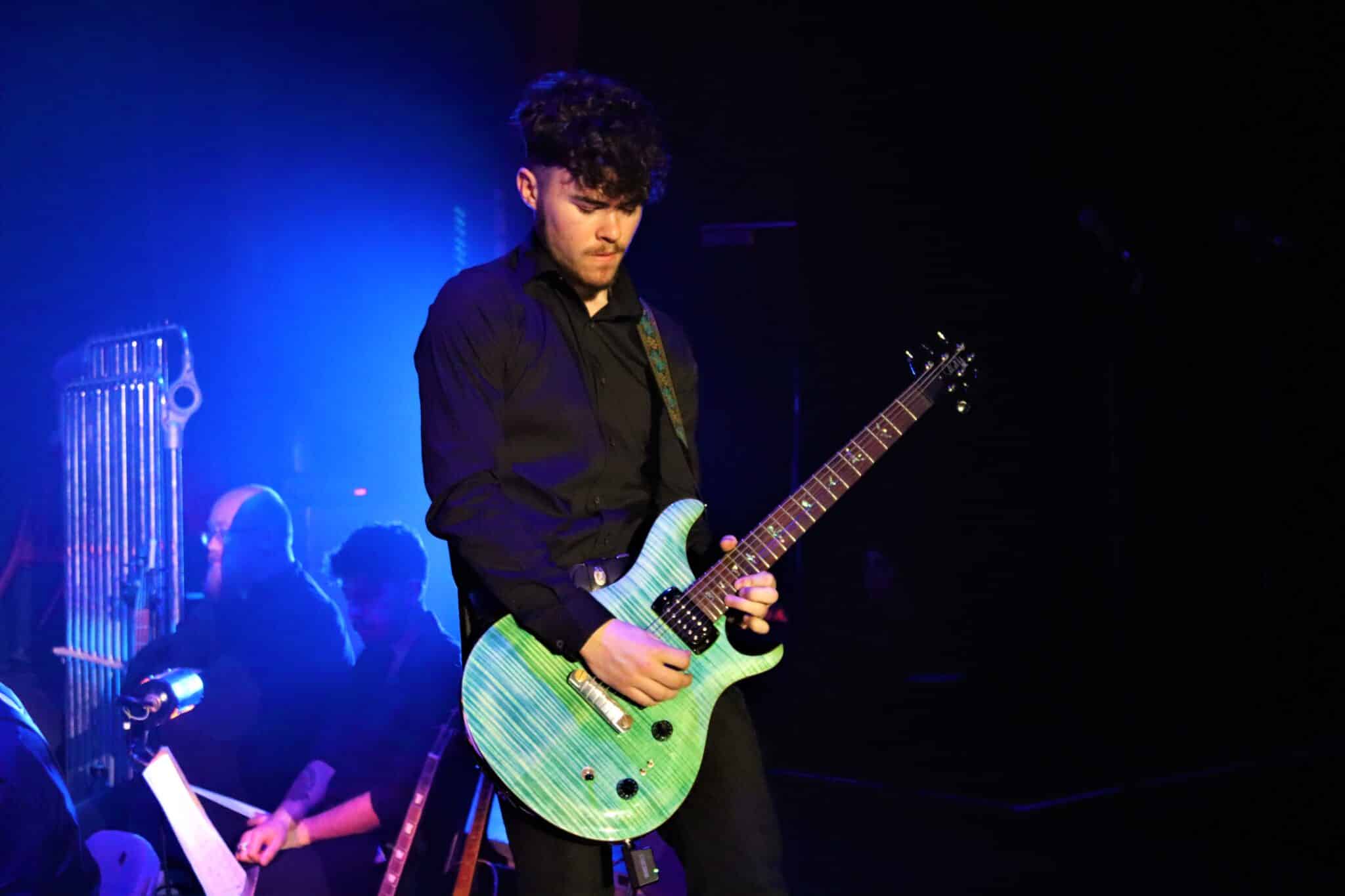 Student plays a guitar on stage.