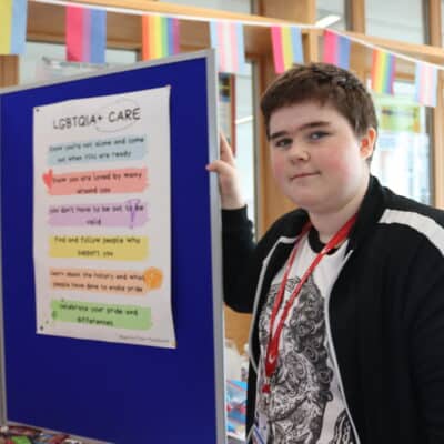 Student showcasing LGBTQIA+ care poster at event