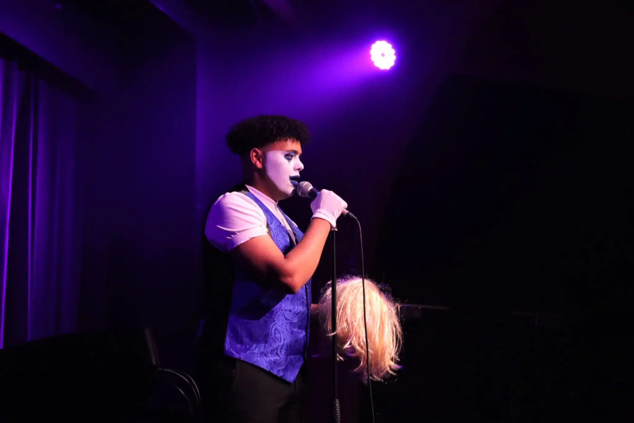 Compare on the stage holding wig