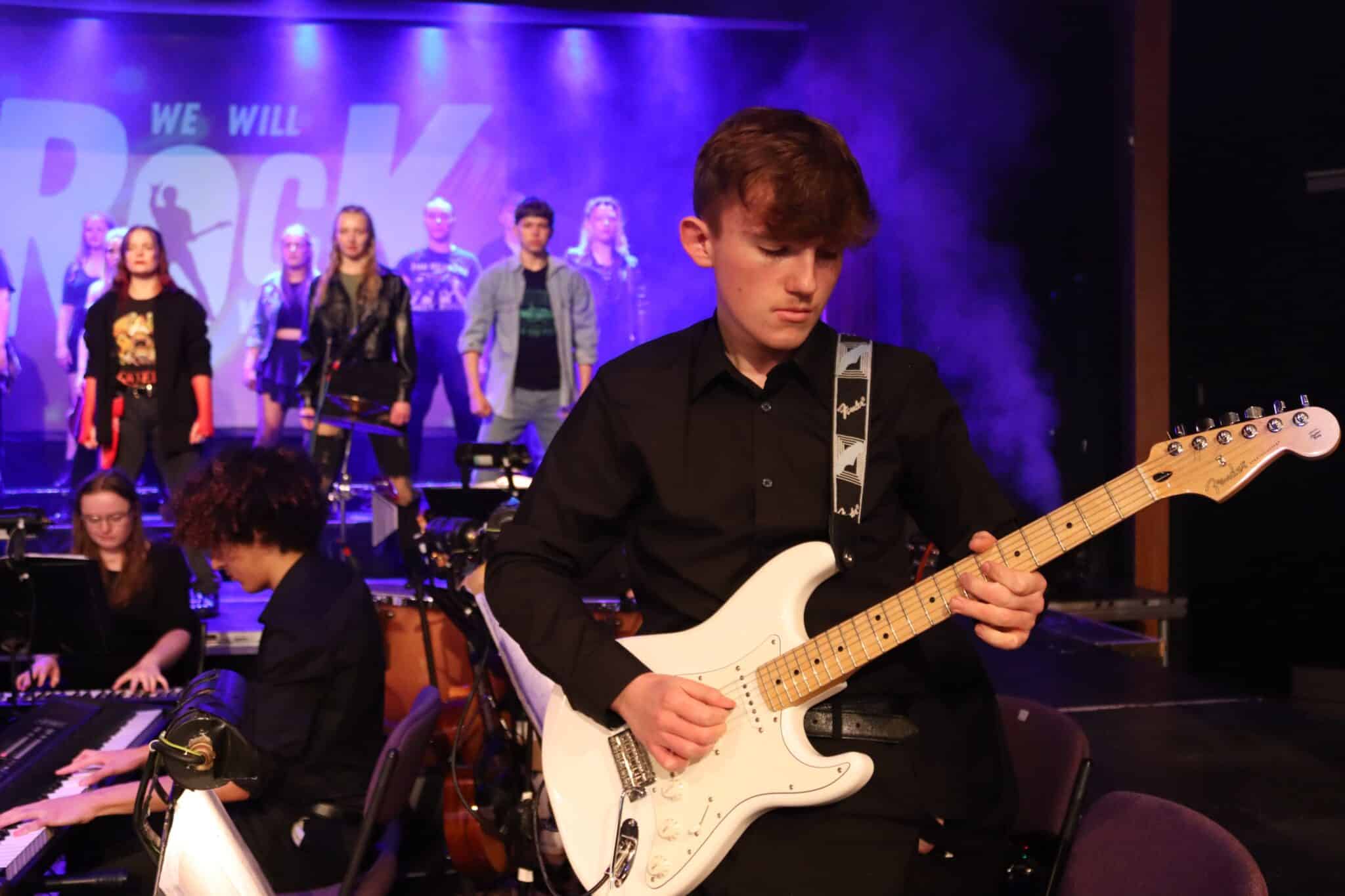 Student plays a guitar on stage.