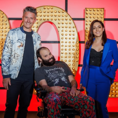 Three people, one woman and two men smiling in front of big letters