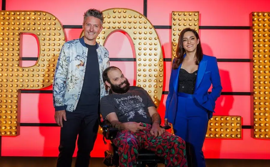 Three people, one woman and two men smiling in front of big letters