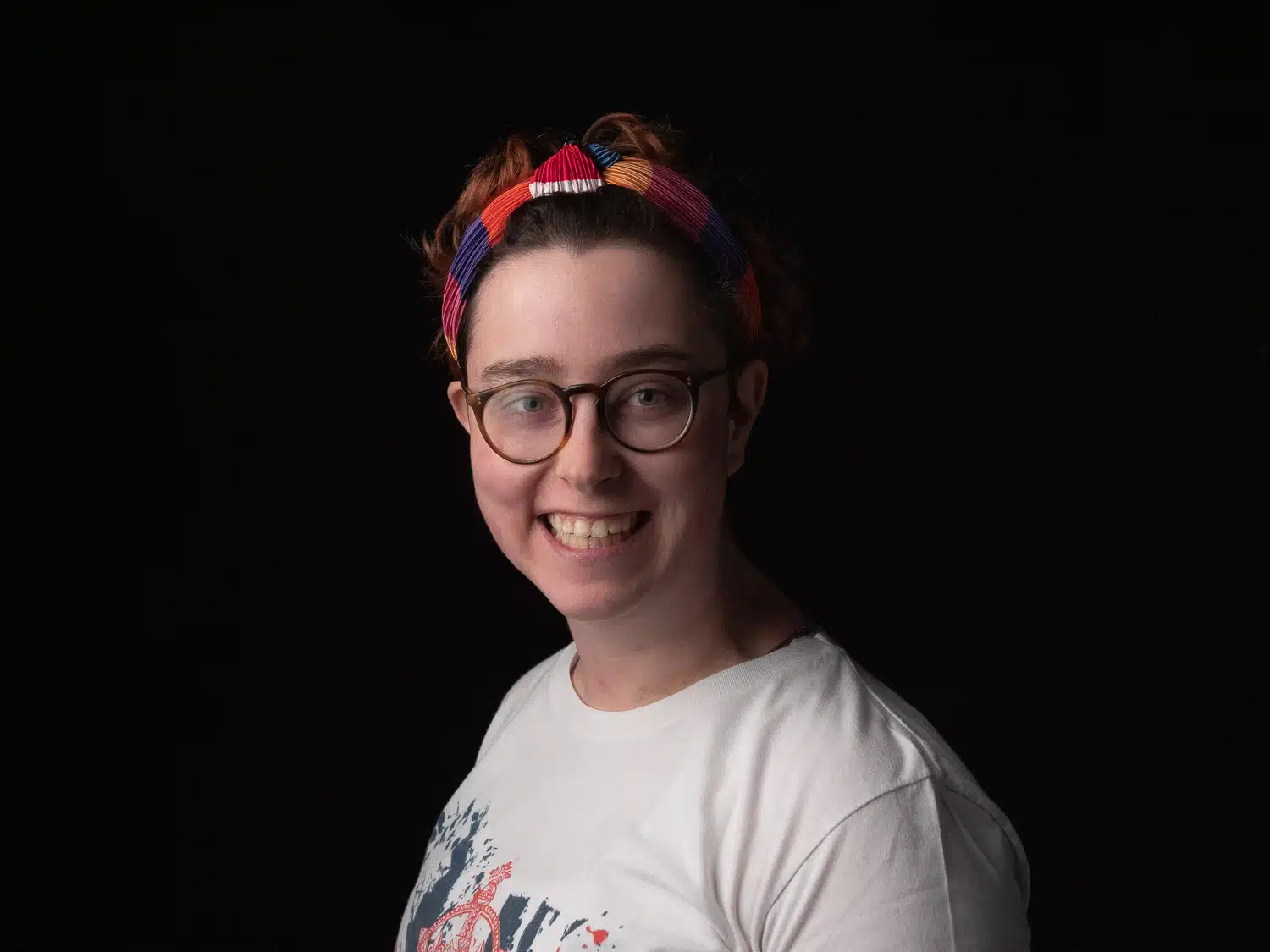 Person smiling at a camera wearing glasses and headband