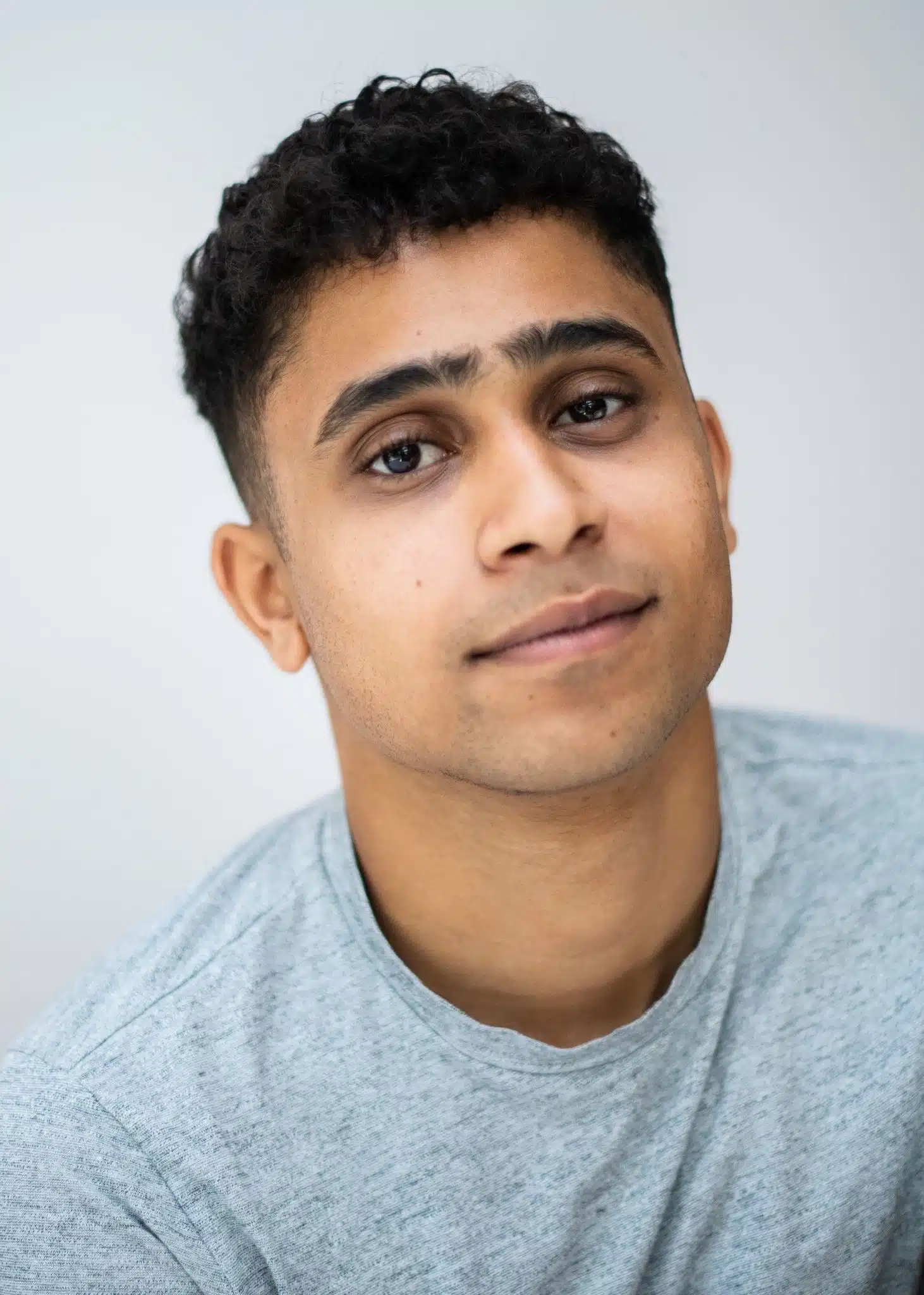 Man in a grey tshirt smiling at a camera