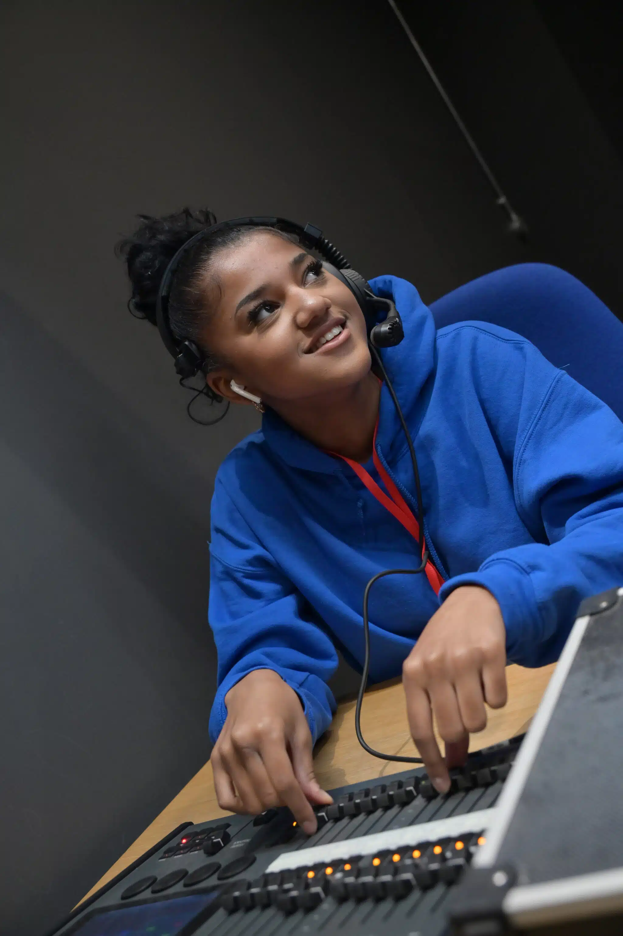 Girl in blue hoodie smiling in a radio studio