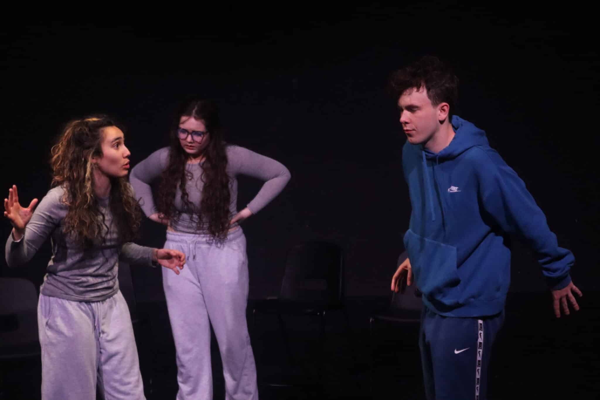 3 actors in grey on stage