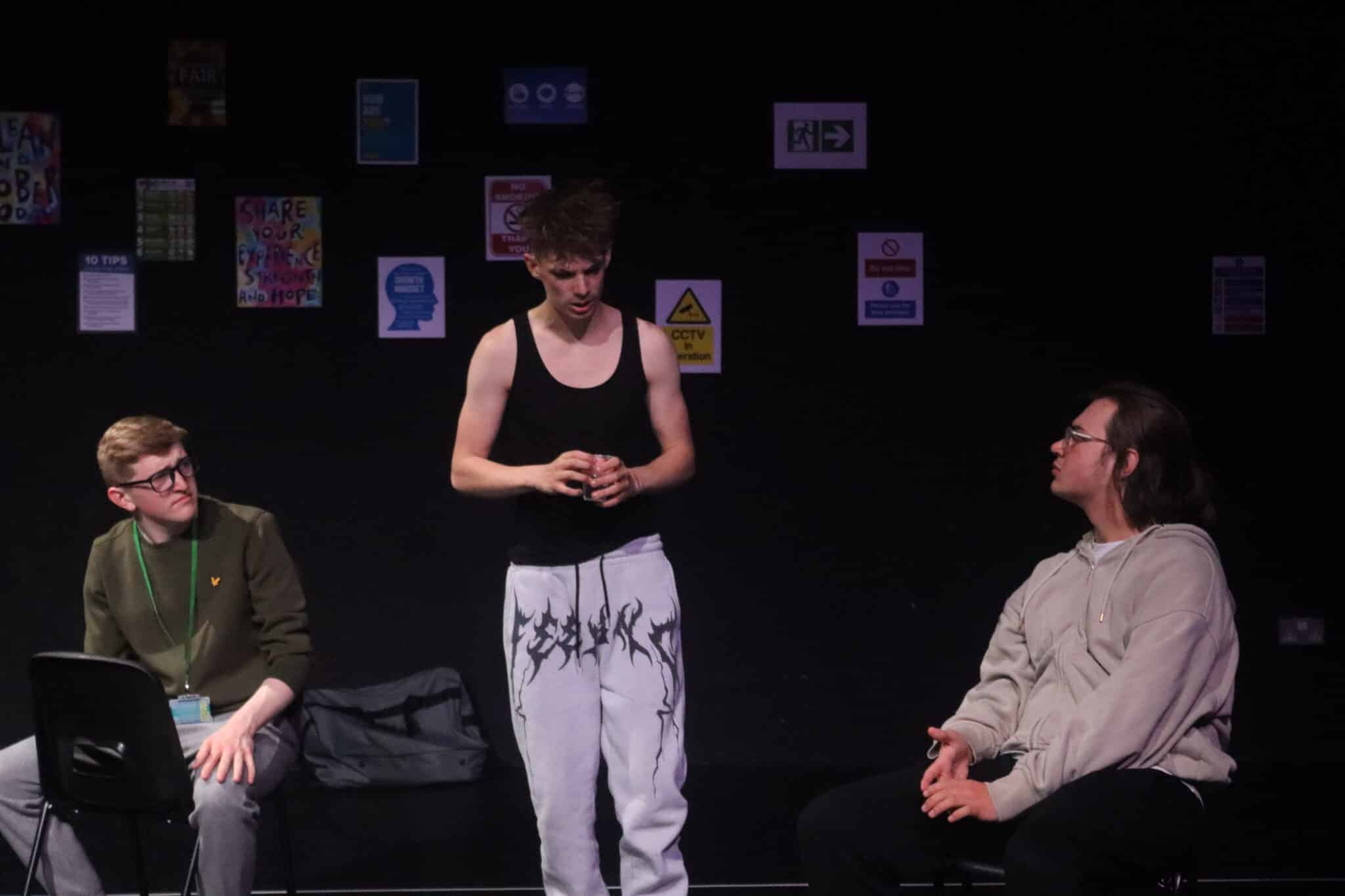 3 actors on stage, with posters in the background