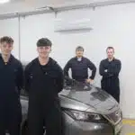 4 student stood in front of electric vehicle