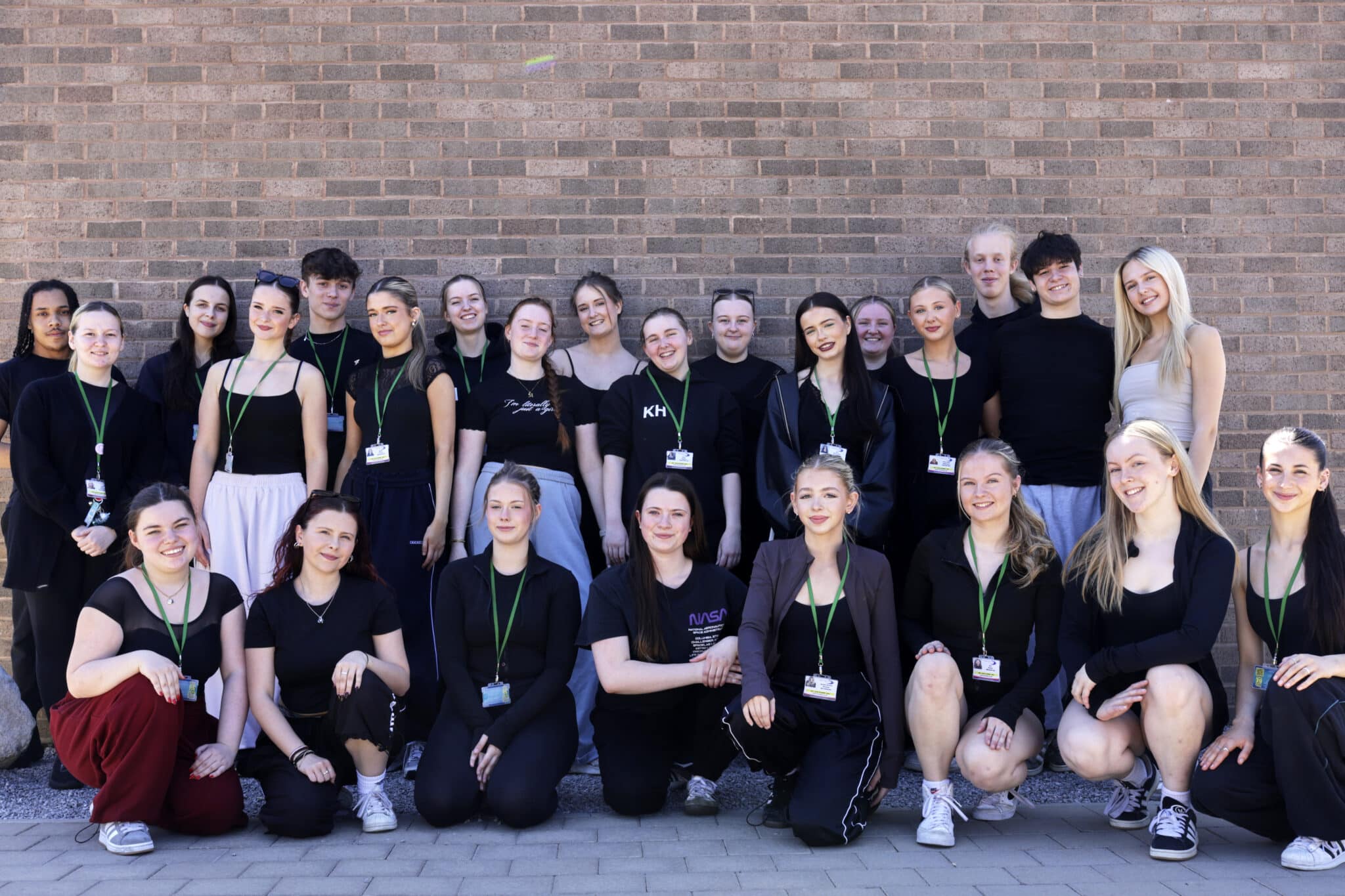 Students stood in front of a brick wall