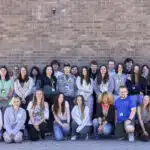 Students stood in front of a brick wall.