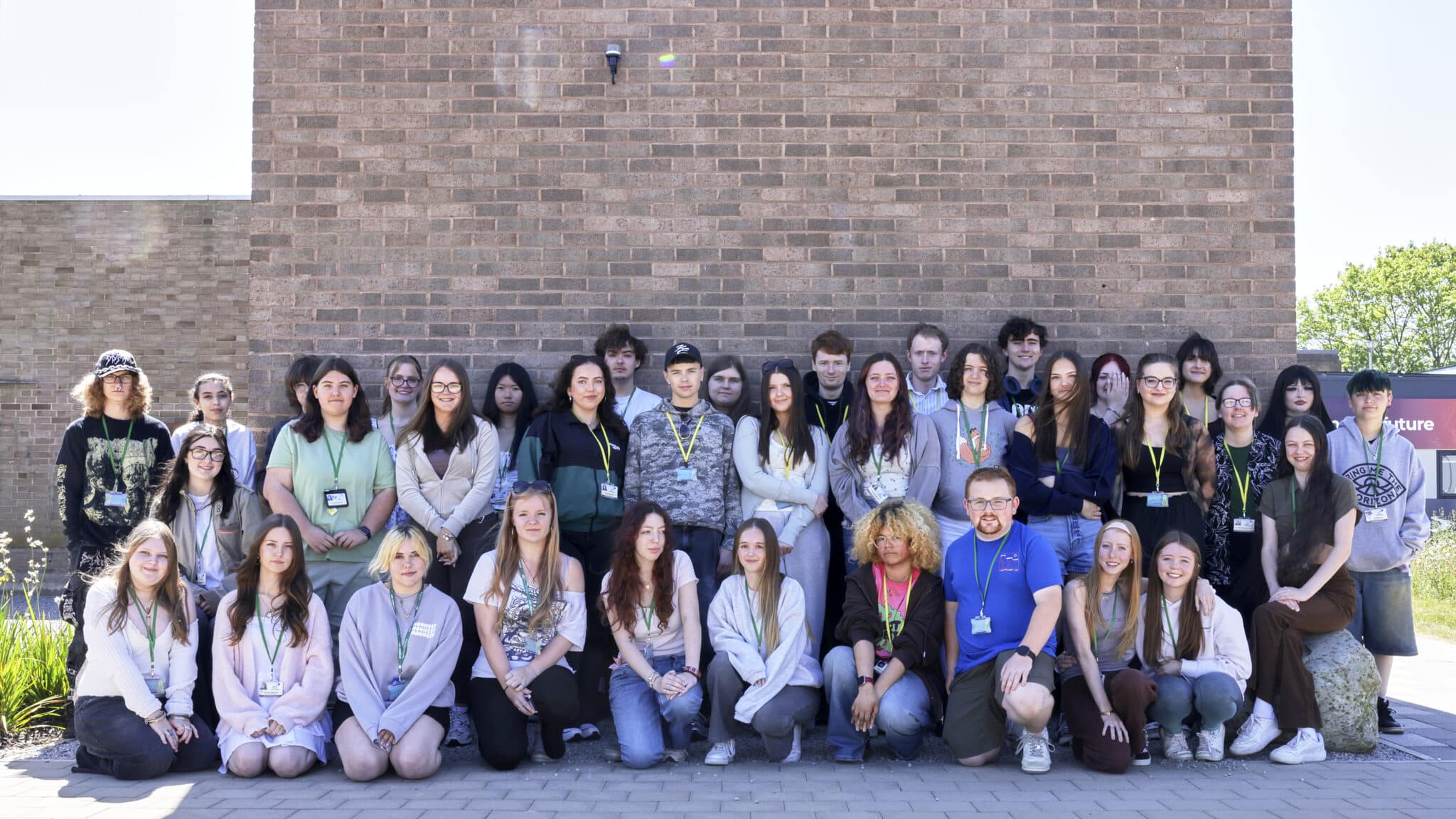 Students stood in front of a brick wall.