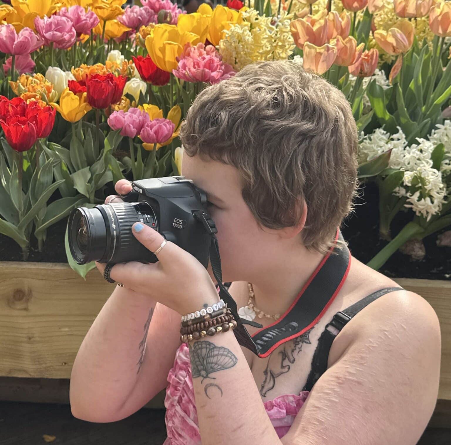 student with a camera infront of tulips