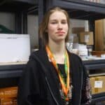 Student standing infront of art supply shelves