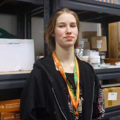 Student standing infront of art supply shelves