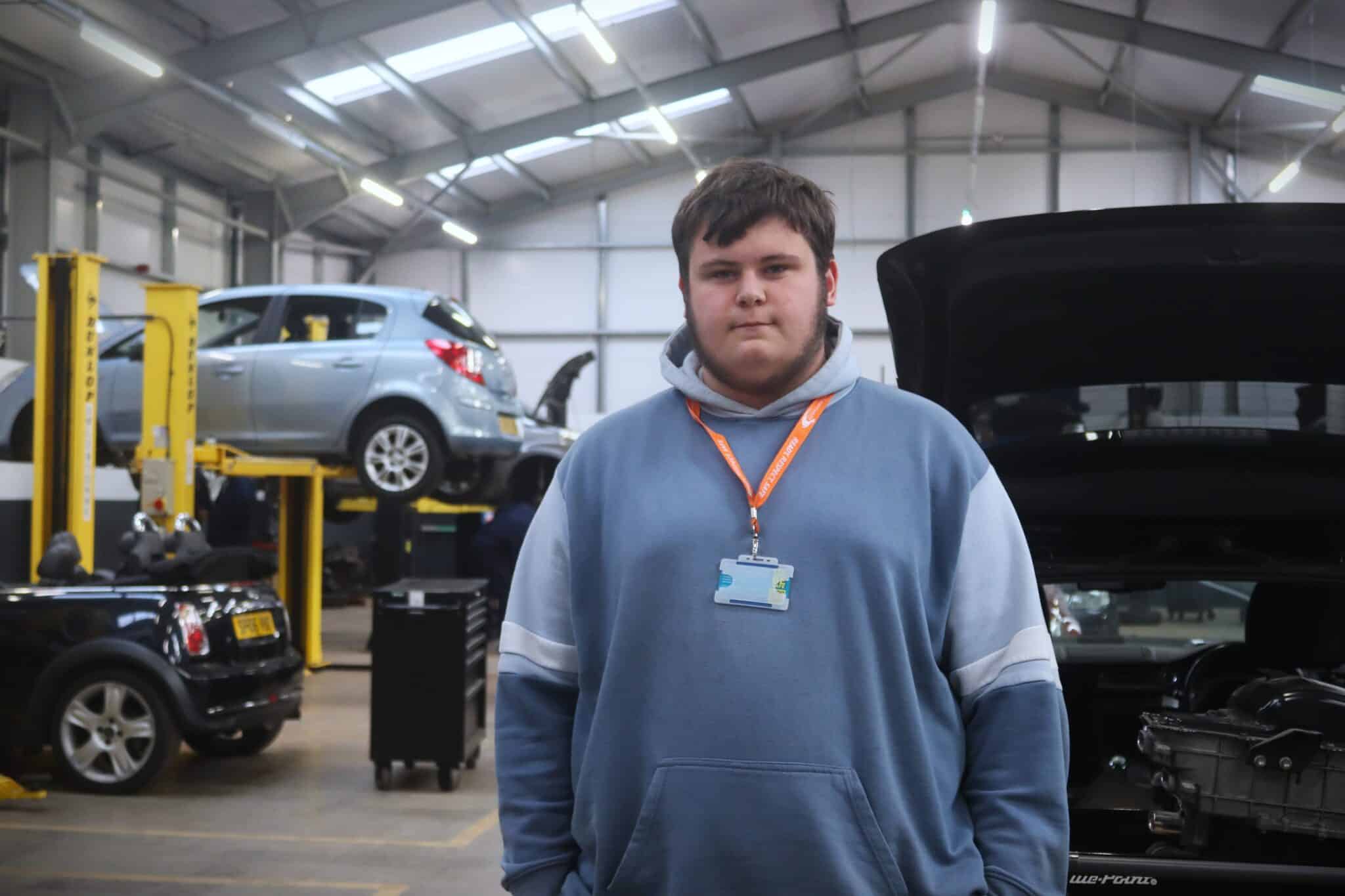 student standing infront of vehicle workshop
