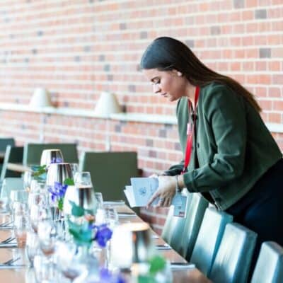 person setting a table in front of a red brick wall