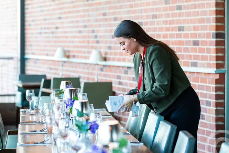 person setting a table in front of a red brick wall