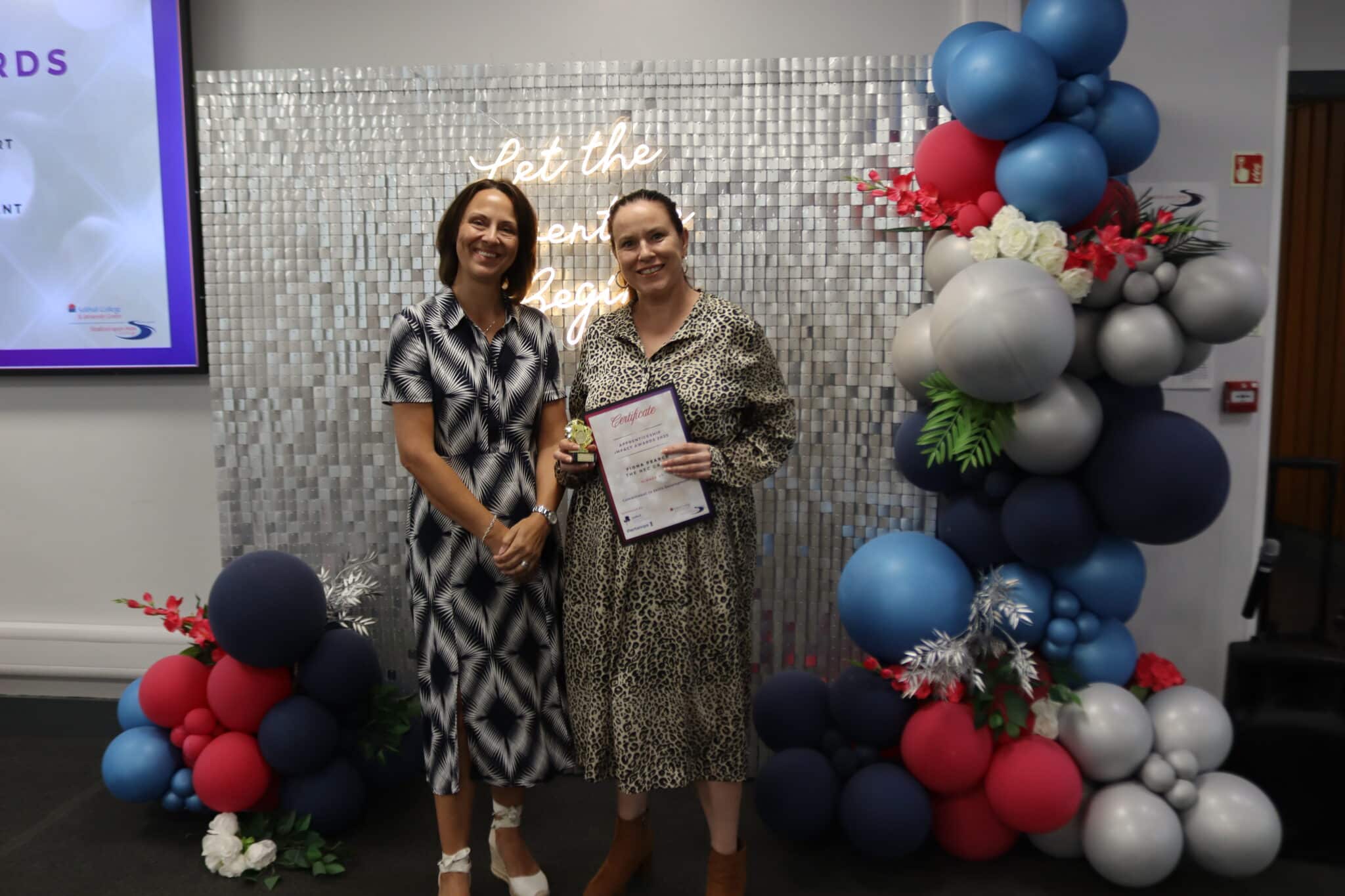 person receiving award next to balloons