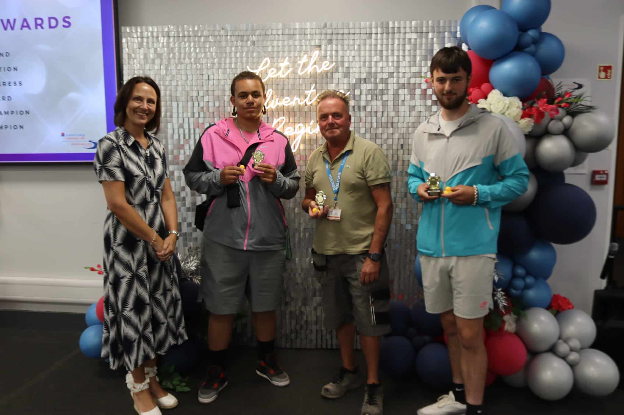 four people stood in front of sparkly backdrop with awards