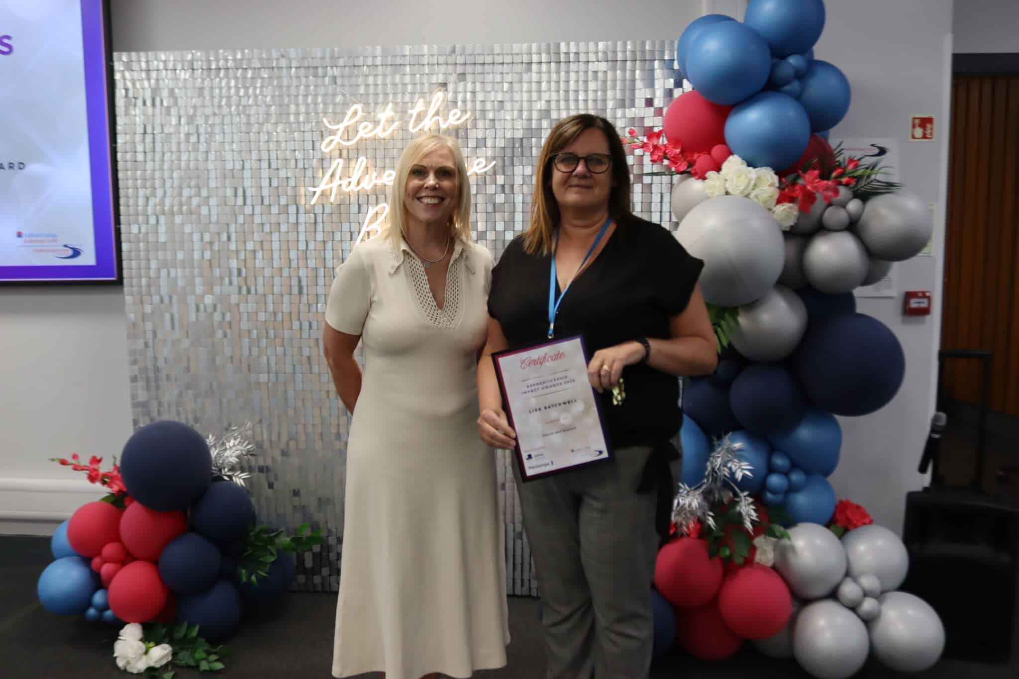 award winner with certificate in front of sparkly backdrop