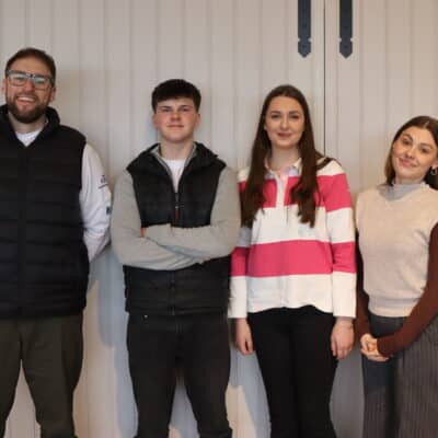 employer and apprentices standing in front of a white wall