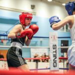 2 boxers in ring, one in red mits one in blue