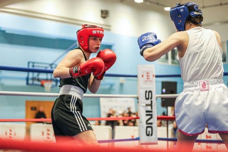 2 boxers in ring, one in red mits one in blue