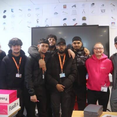 students standing with visitor in front of computer screen