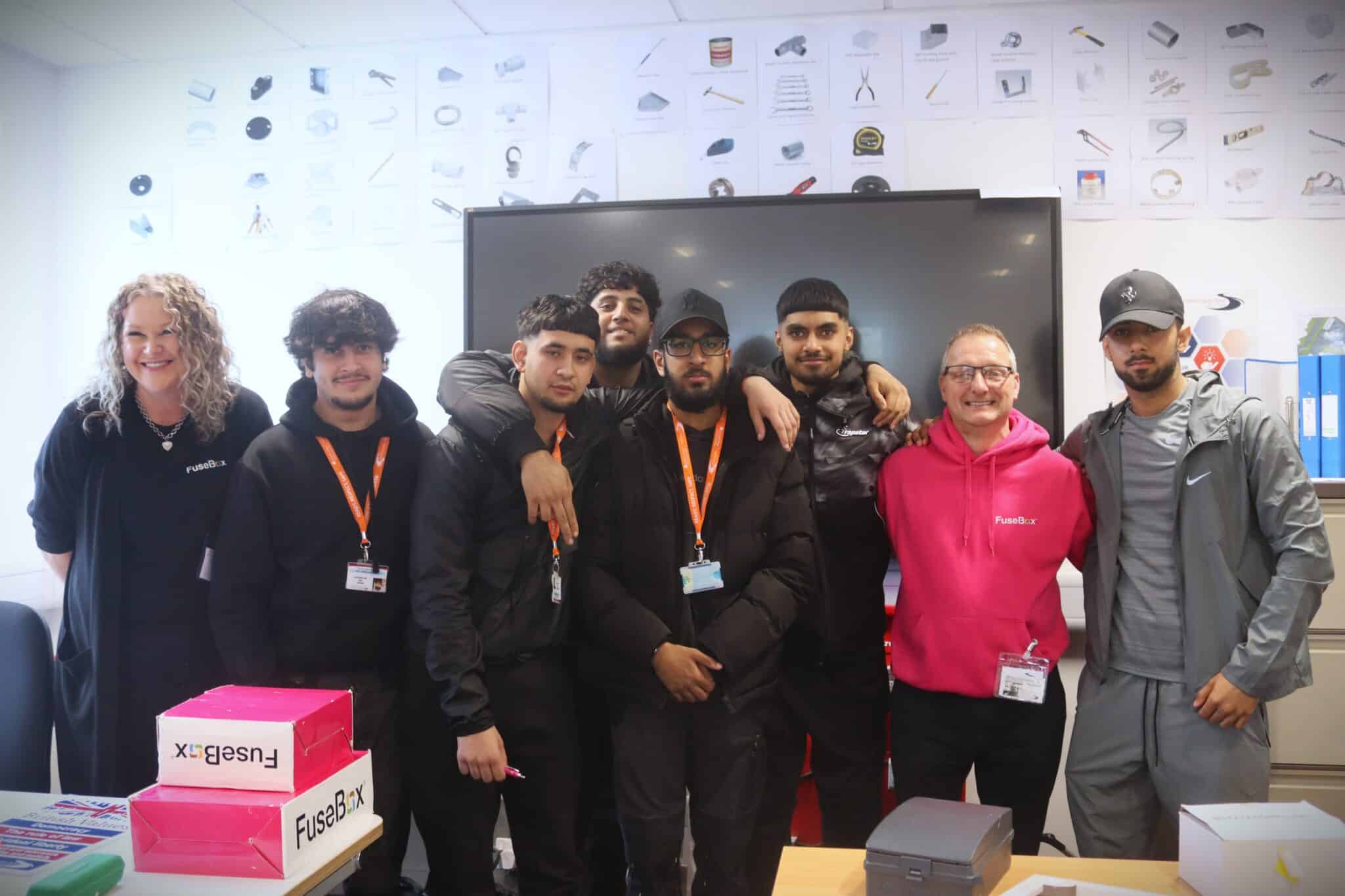 students standing with visitor in front of computer screen