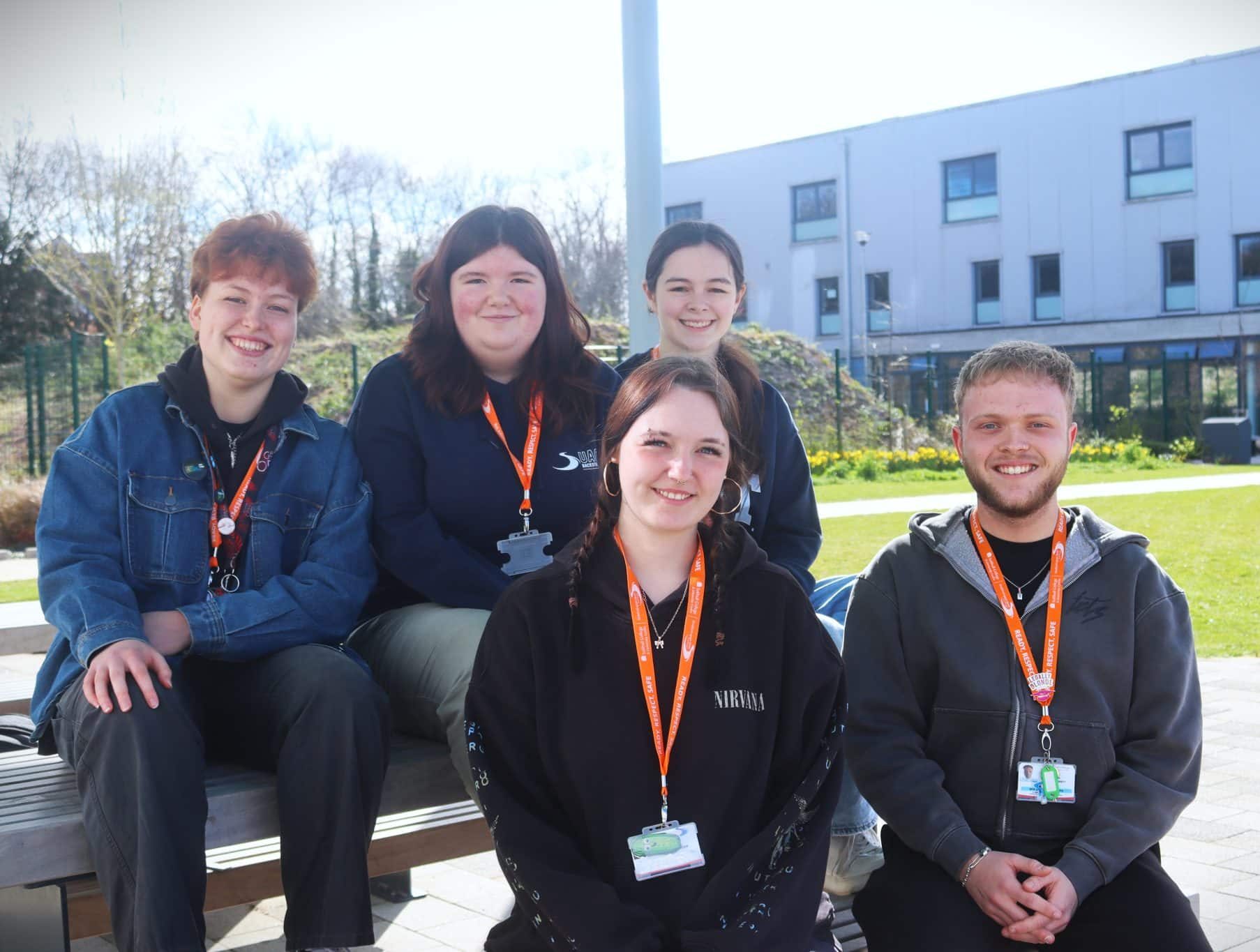 students sat on bench in campus grounds