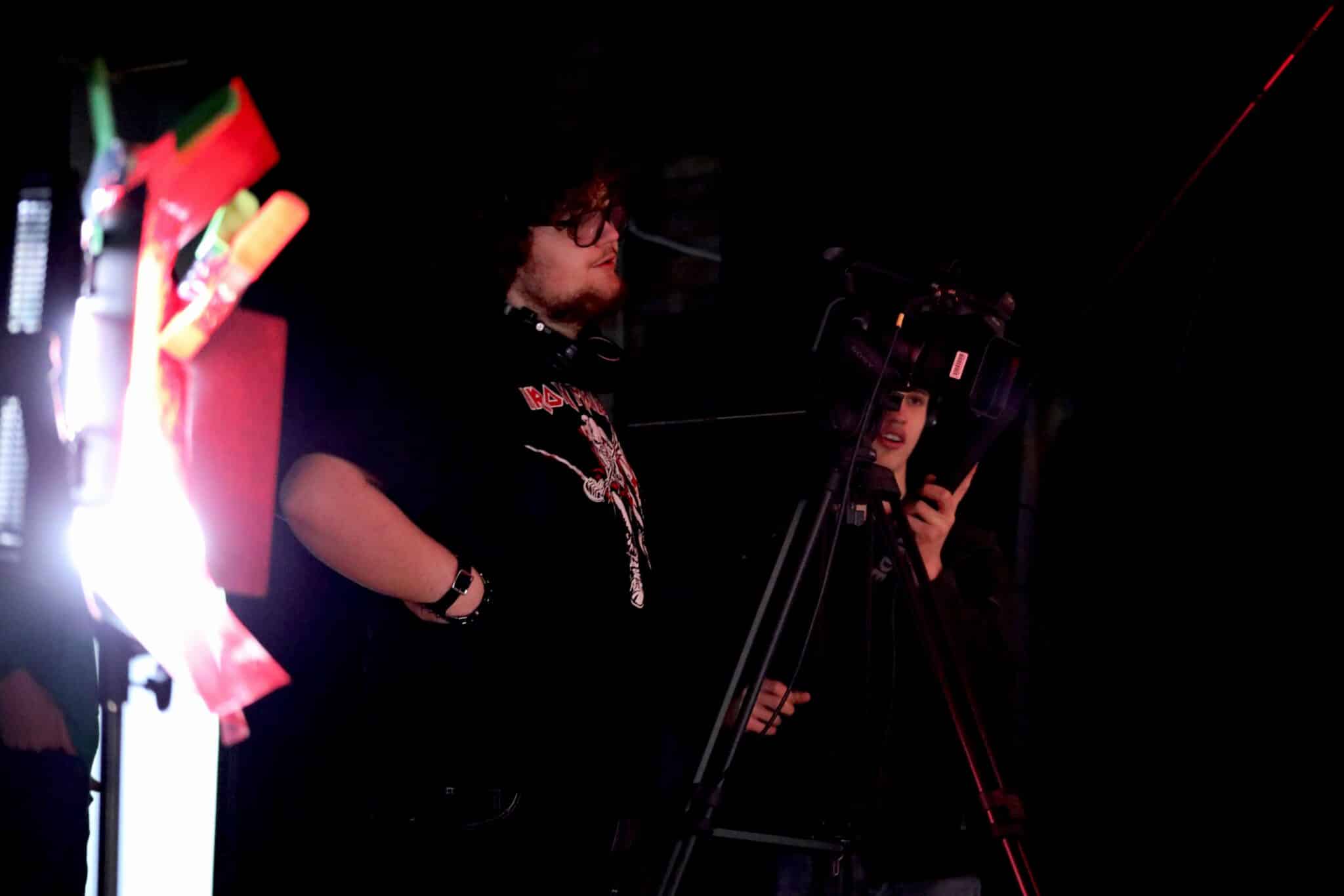 person stood in darkness directing film