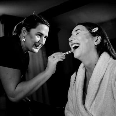 2 woman with one dressed in black the other in white doing make up