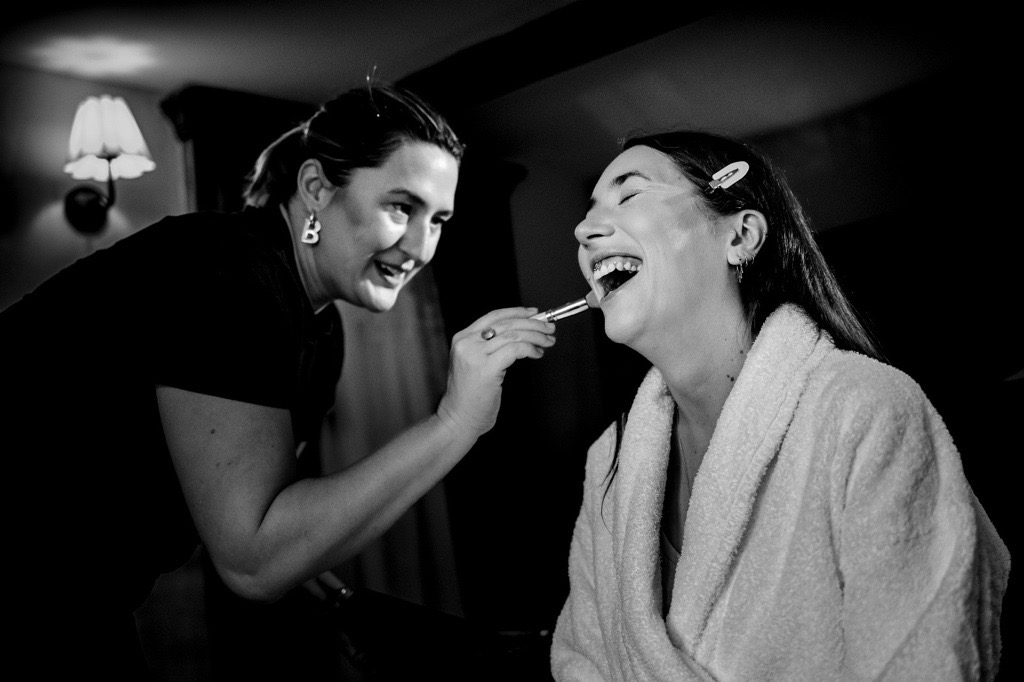 2 woman with one dressed in black the other in white doing make up