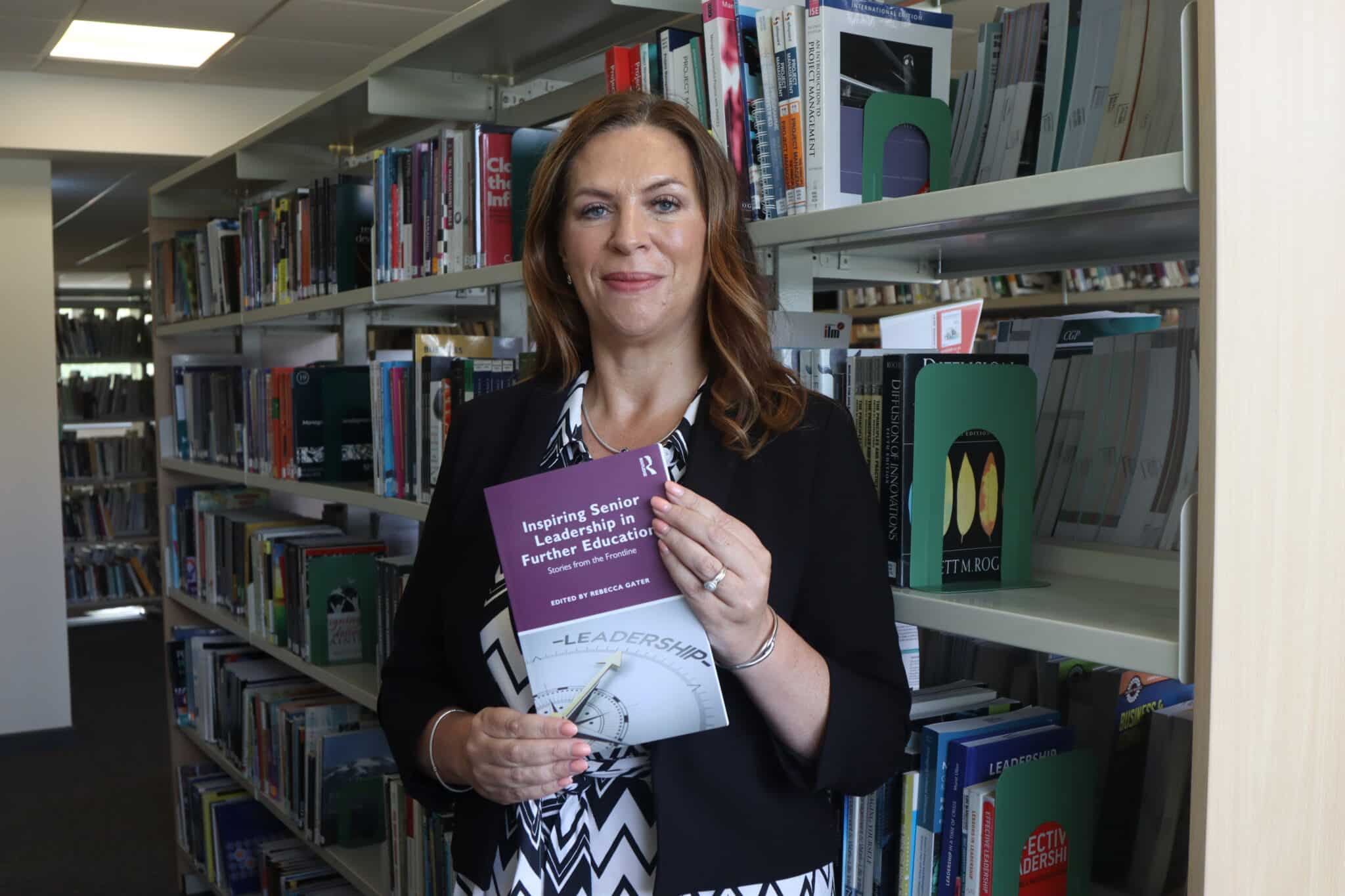 person stood in front of bookshelves holding book